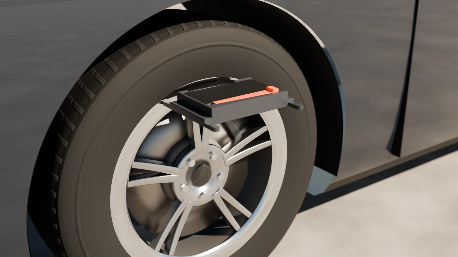 The Rim Reader bracket with a phone clamped in it, lying flat on top of a car's front wheel with its prongs on the rim's lip